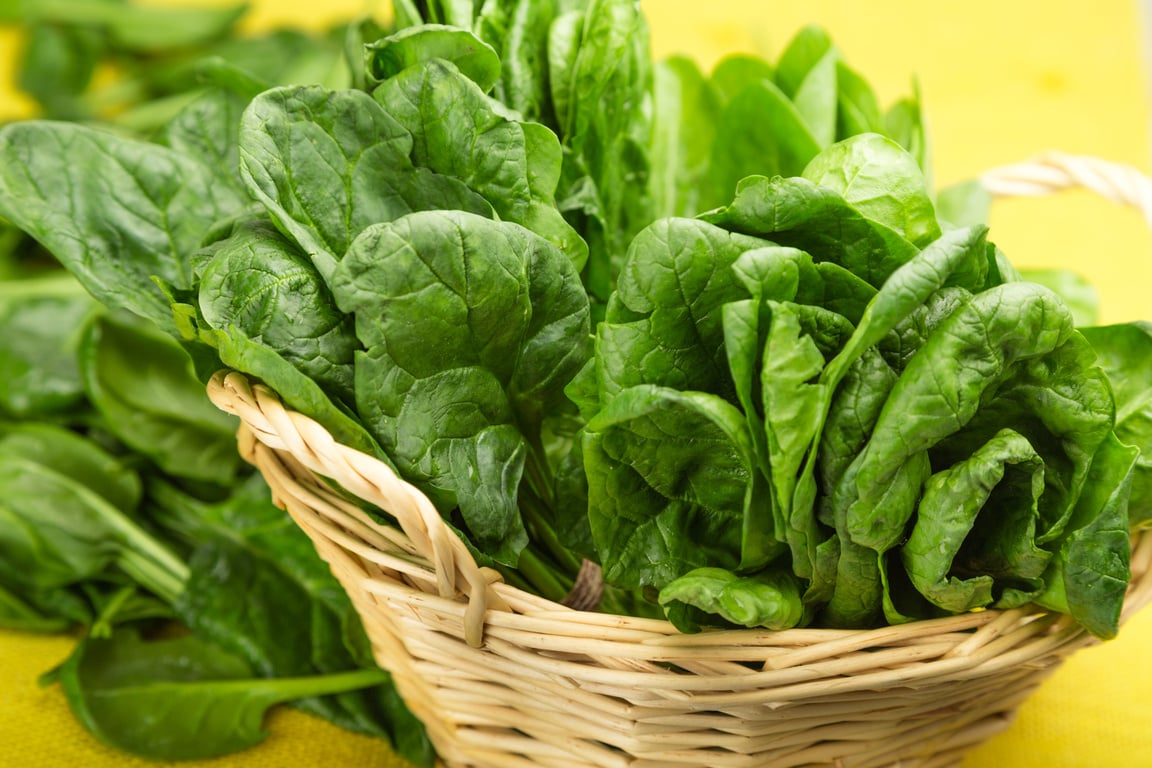 Young Spinach Leaves In Basket On Yellow Tablecloth